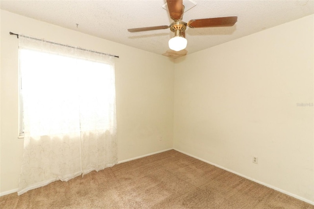 carpeted spare room featuring ceiling fan, baseboards, and a textured ceiling