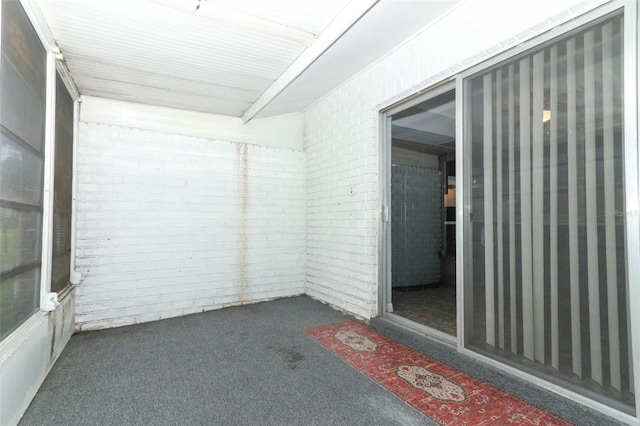 unfurnished room with dark carpet and brick wall