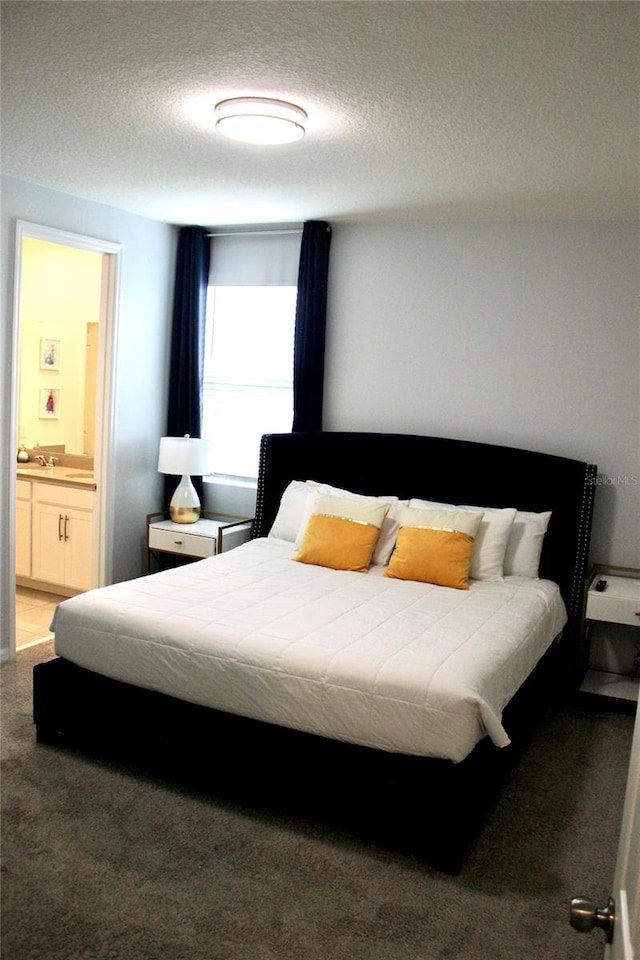 carpeted bedroom with sink, ensuite bath, and a textured ceiling