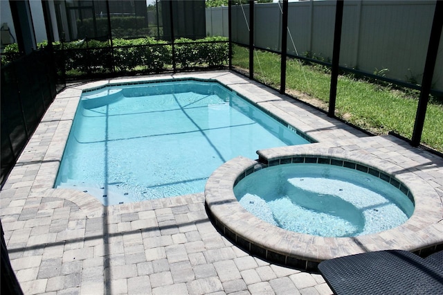 view of swimming pool featuring an in ground hot tub and a lanai