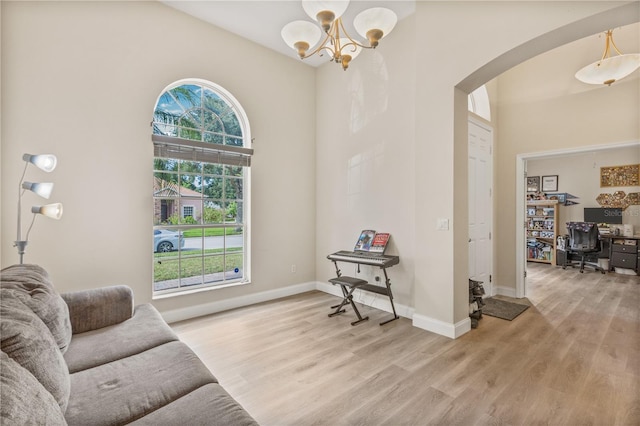 living room with plenty of natural light, a chandelier, and light hardwood / wood-style floors