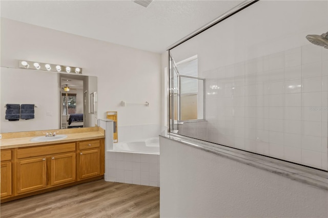 bathroom featuring hardwood / wood-style flooring, shower with separate bathtub, vanity, and ceiling fan