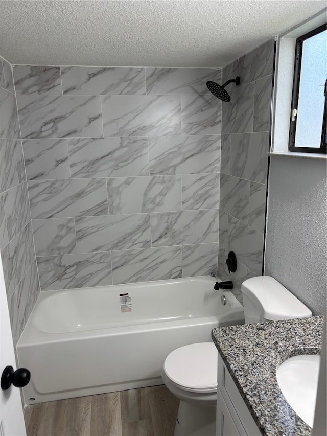 full bathroom with tiled shower / bath, a textured ceiling, and toilet