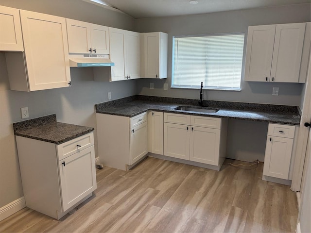 kitchen featuring sink, white cabinets, light hardwood / wood-style floors, and dark stone countertops