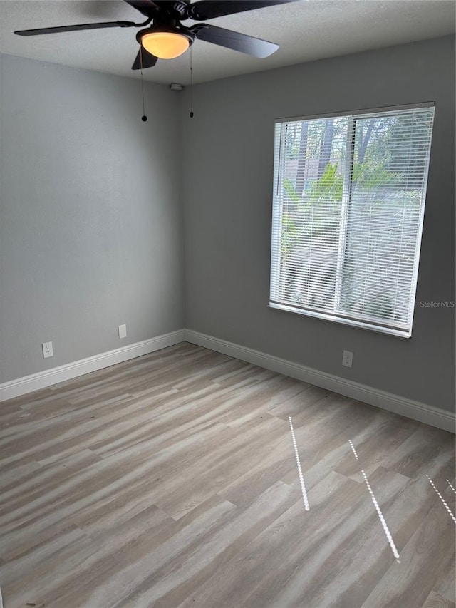 unfurnished room featuring a textured ceiling, light wood-type flooring, and ceiling fan