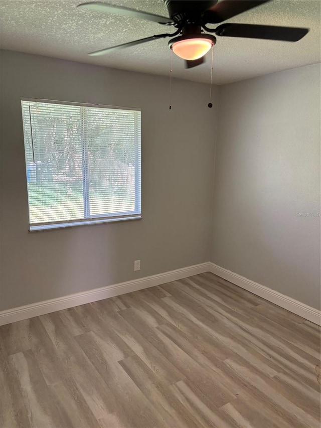 unfurnished room with ceiling fan, a textured ceiling, and light wood-type flooring