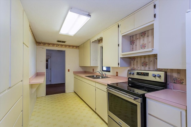 kitchen featuring electric range, sink, and light carpet