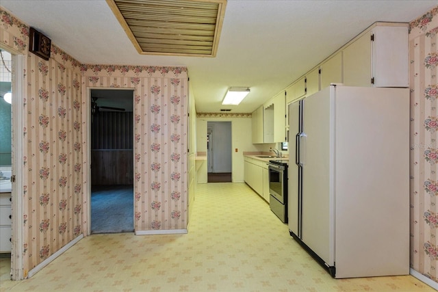 kitchen with sink, white fridge, stainless steel electric stove, and light colored carpet