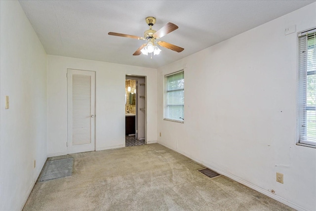 unfurnished bedroom featuring multiple windows, light carpet, and ceiling fan