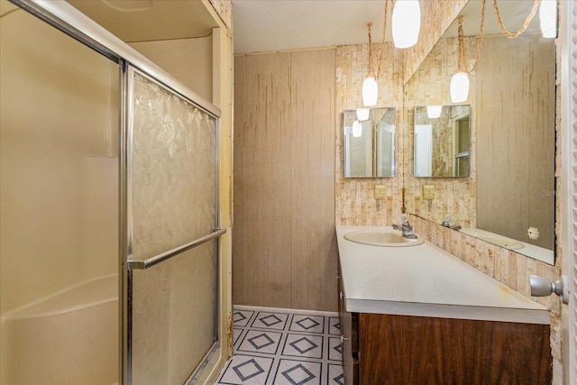 bathroom featuring a shower with door, vanity, and wood walls