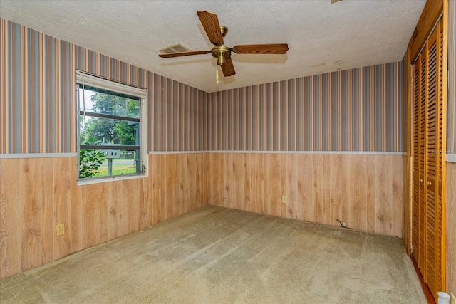 carpeted empty room with a textured ceiling and ceiling fan