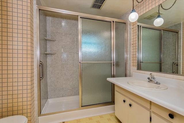 bathroom featuring tile patterned flooring, a shower with door, toilet, and vanity