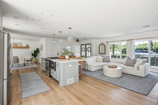 kitchen featuring ornamental molding, a center island, light wood-type flooring, and stainless steel appliances