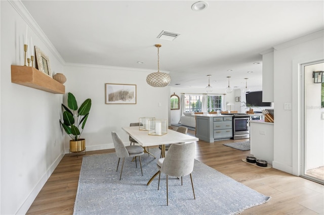 dining space featuring crown molding and light wood-type flooring