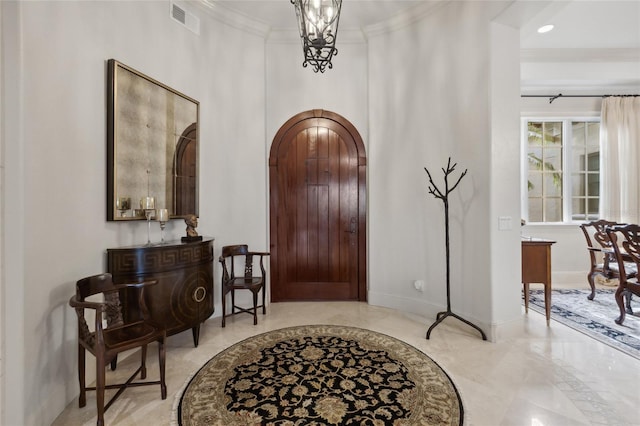 entryway with baseboards, visible vents, arched walkways, crown molding, and a chandelier