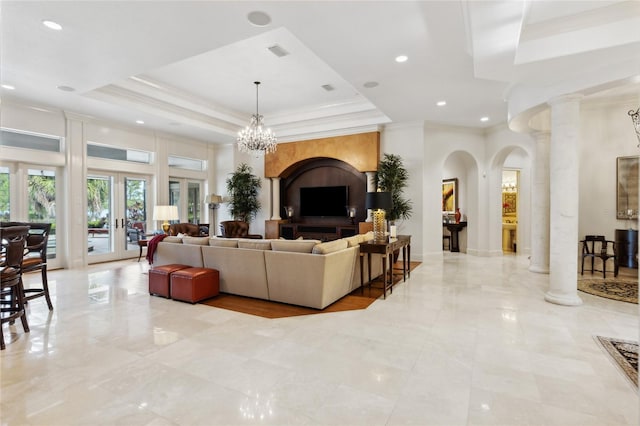 living room featuring crown molding, a tray ceiling, visible vents, and ornate columns