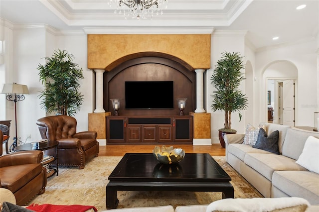 living area with ornamental molding, a raised ceiling, and wood finished floors