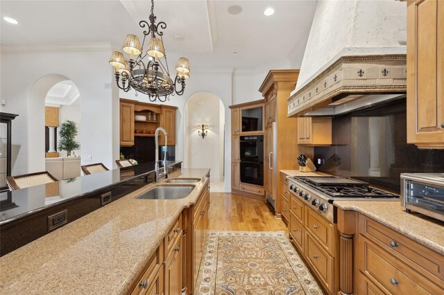 kitchen with dobule oven black, stainless steel gas cooktop, arched walkways, and a sink