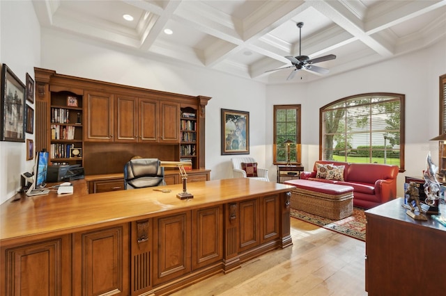 office area with light wood finished floors, coffered ceiling, a ceiling fan, a towering ceiling, and beam ceiling