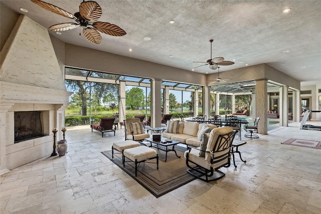 living area featuring a ceiling fan, a sunroom, stone tile flooring, a fireplace, and recessed lighting