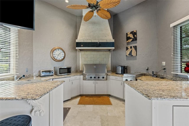 kitchen featuring refrigerator, a peninsula, a healthy amount of sunlight, custom exhaust hood, and stainless steel microwave