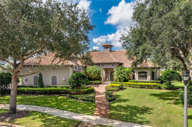 mediterranean / spanish home with a tiled roof, a front yard, and stucco siding