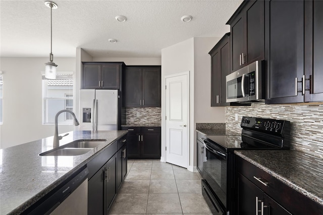 kitchen featuring decorative light fixtures, appliances with stainless steel finishes, a sink, dark stone countertops, and dark brown cabinets