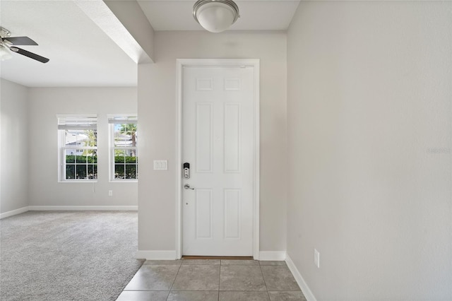 foyer entrance with light carpet, ceiling fan, baseboards, and light tile patterned floors