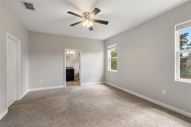 unfurnished bedroom featuring carpet floors, visible vents, a ceiling fan, connected bathroom, and baseboards