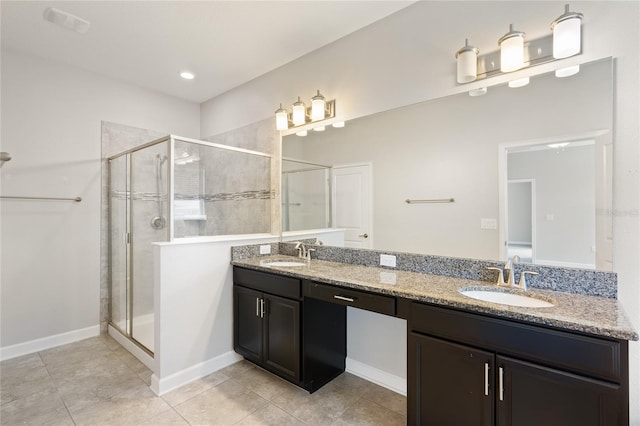 full bathroom featuring baseboards, double vanity, a sink, and a shower stall