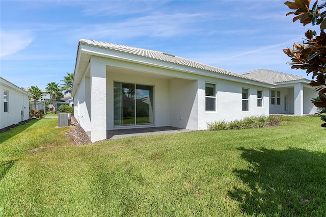 rear view of property with central AC unit and a lawn