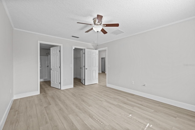 unfurnished bedroom with a textured ceiling, ceiling fan, light hardwood / wood-style floors, a walk in closet, and a closet