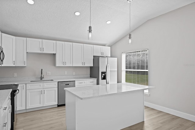 kitchen featuring hanging light fixtures, stainless steel appliances, vaulted ceiling, and white cabinets