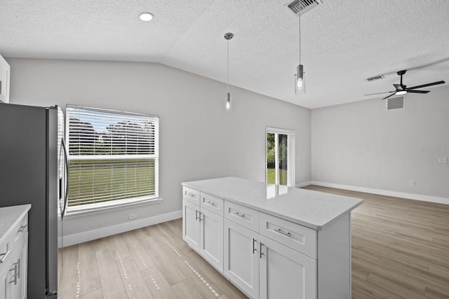 kitchen with white cabinets, ceiling fan, light hardwood / wood-style floors, stainless steel fridge, and vaulted ceiling