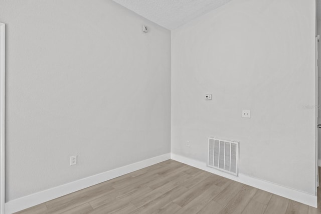 unfurnished room with light wood-type flooring and a textured ceiling