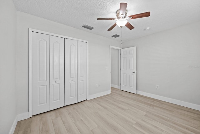 unfurnished bedroom with light hardwood / wood-style floors, a closet, a textured ceiling, and ceiling fan