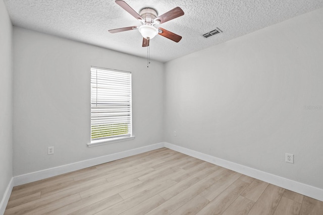 spare room featuring light wood-type flooring, ceiling fan, and a textured ceiling