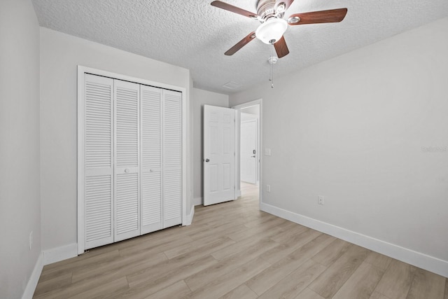 unfurnished bedroom with a textured ceiling, a closet, light wood-type flooring, and ceiling fan