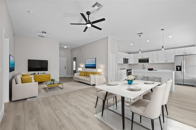 dining area with light hardwood / wood-style floors, sink, and ceiling fan