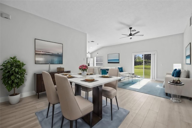 dining area featuring lofted ceiling, a textured ceiling, light wood-type flooring, and ceiling fan