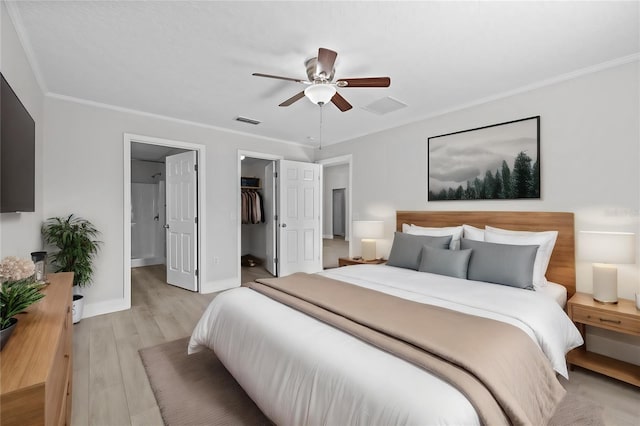 bedroom featuring a closet, crown molding, light wood-type flooring, a walk in closet, and ceiling fan