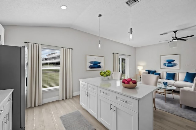 kitchen with white cabinets, stainless steel refrigerator, light wood-type flooring, lofted ceiling, and ceiling fan