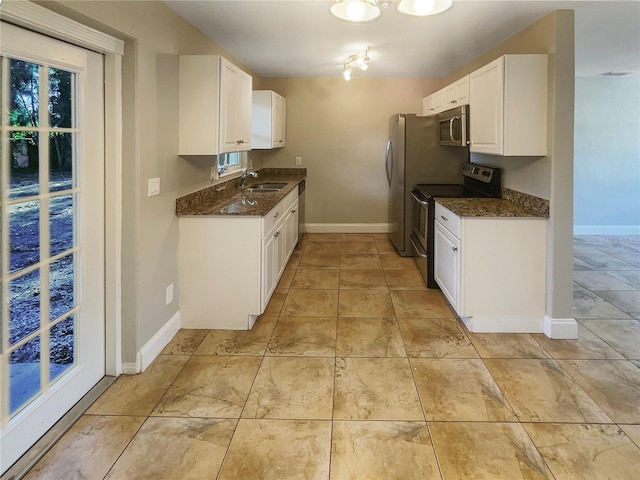 kitchen with white cabinetry, dark stone countertops, light tile patterned floors, appliances with stainless steel finishes, and sink