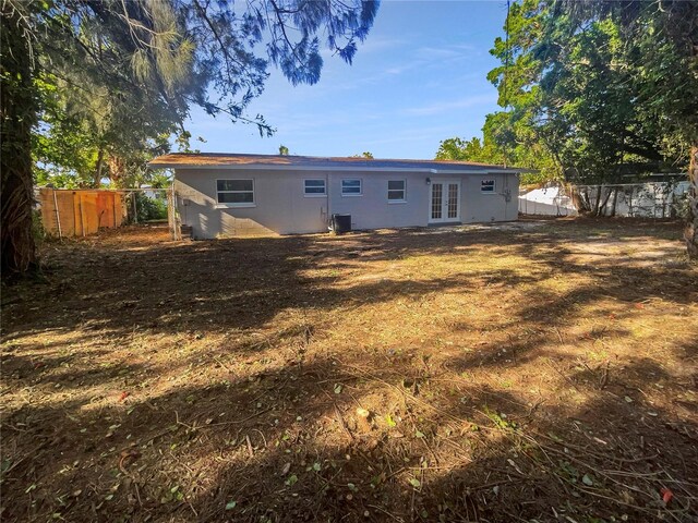 back of house featuring french doors, central AC, and a lawn