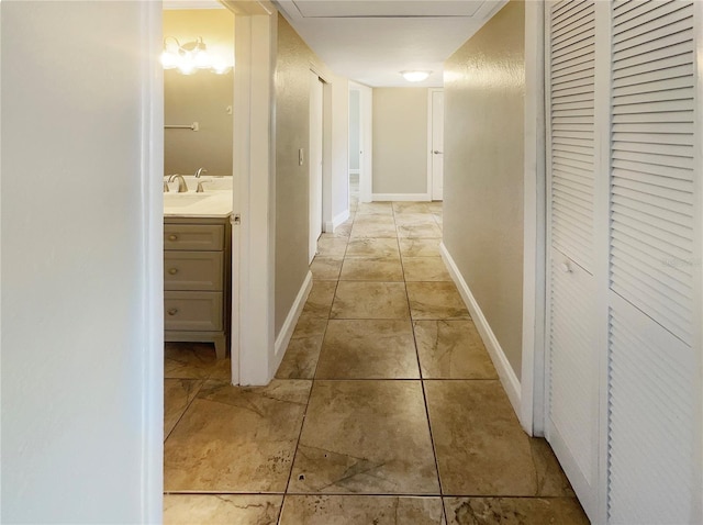 corridor featuring sink and light tile patterned flooring