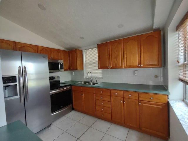 kitchen featuring light tile patterned floors, lofted ceiling, appliances with stainless steel finishes, and sink