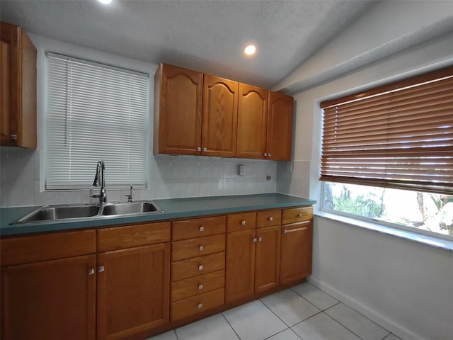 kitchen featuring sink, light tile patterned flooring, lofted ceiling, and backsplash