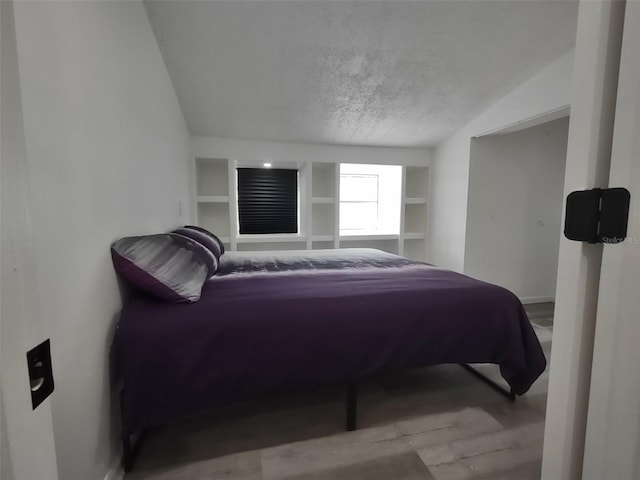 bedroom featuring a textured ceiling, hardwood / wood-style flooring, and vaulted ceiling