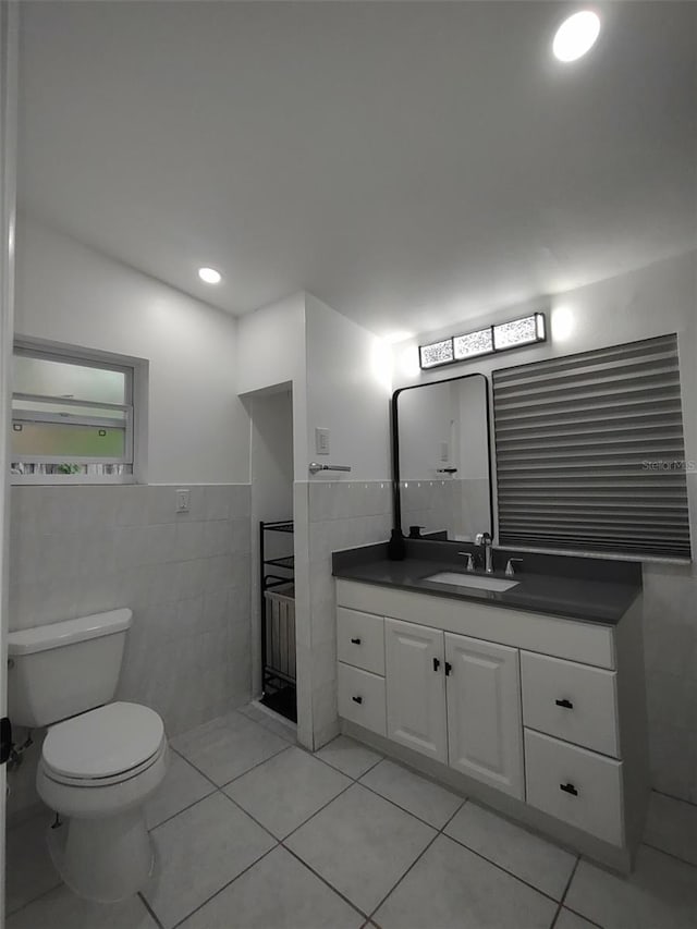 bathroom featuring toilet, vanity, tile patterned flooring, and tile walls