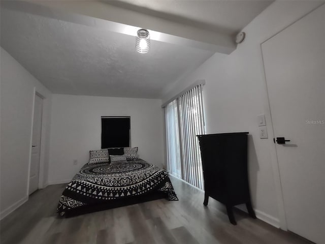 bedroom with beamed ceiling and wood-type flooring